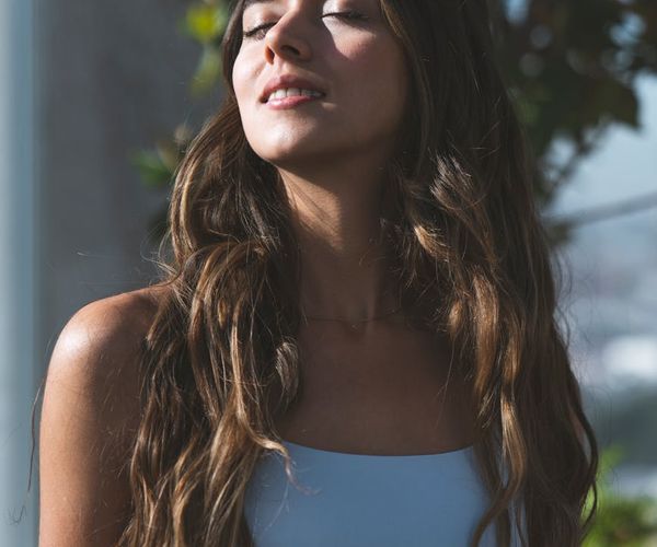 Smiling woman meditating outdoors feeling serene and balanced.